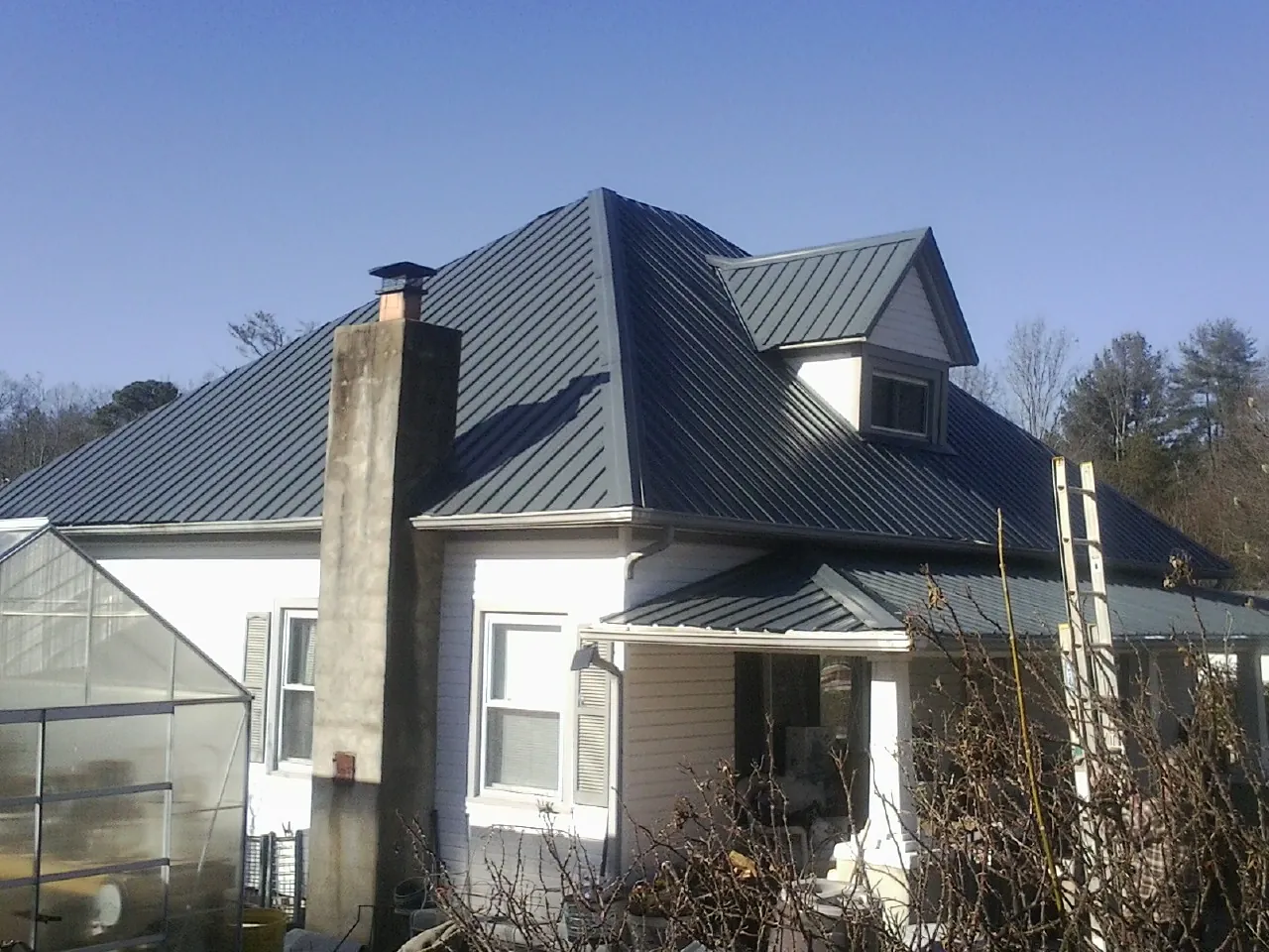 Dark blue standing seam metal roof on a white farmhouse with dormer — Slate & Tile Roof Repair by Roofing Brothers in Redwood