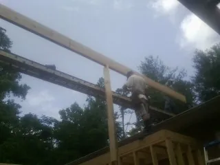 Carpenter setting a ridge beam over a new addition frame — Ice Dam Removal by Roofing Brothers in Redwood