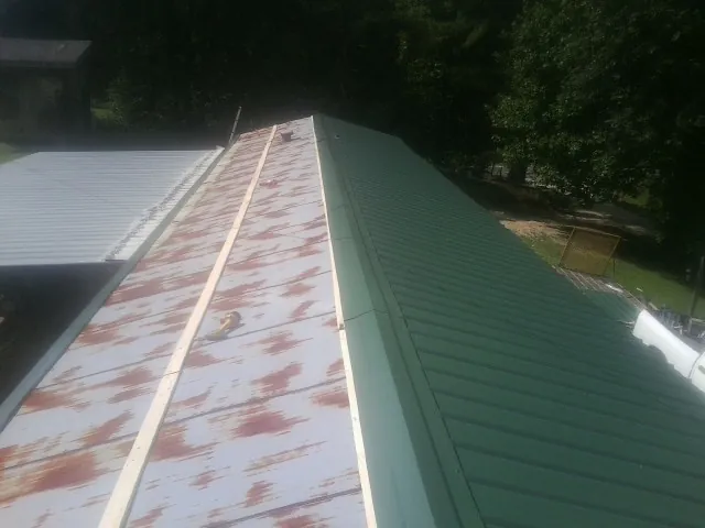Old rusted panels beside newly installed green metal roofing — Wind Damage Roof Repair by Roofing Brothers in Redwood