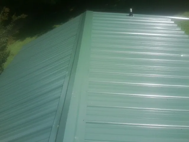 New green metal panels meeting at the ridge of a roof — Flat Roof Repair work by our crew in Redwood