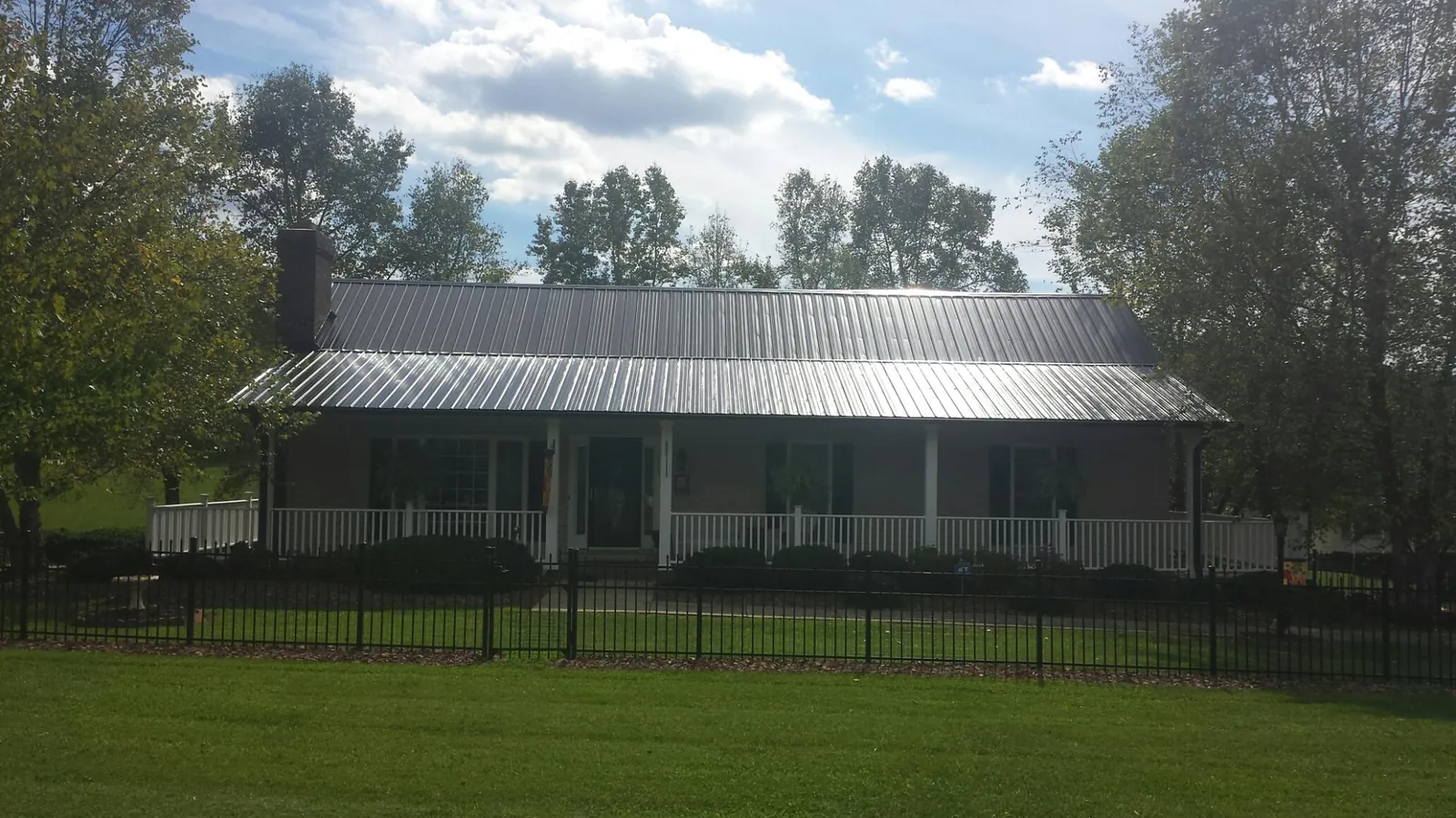 Gray metal roof on a brick ranch with a full width front porch — Gutter Guard Installation work by our crew in Redwood