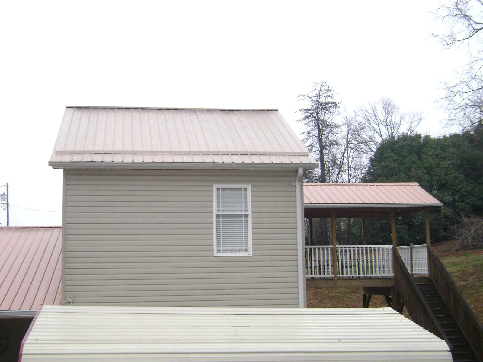 Tan metal roofs on a two story addition and attached porch, from a Roof Replacement job in Redwood