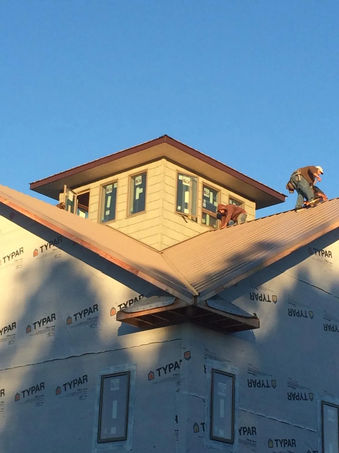 Roofers working around a rooftop cupola on a new metal roof at sunset — Roof Waterproofing in Redwood by Roofing Brothers